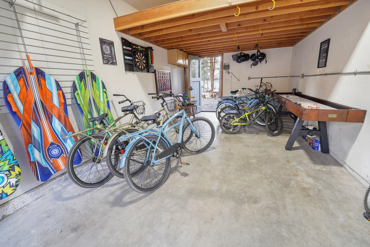 An energetic interior scene showing a row of guest-use bicycles, surfboards, and a foosball table, evoking the spirit of adventure, gear readiness, and fun.