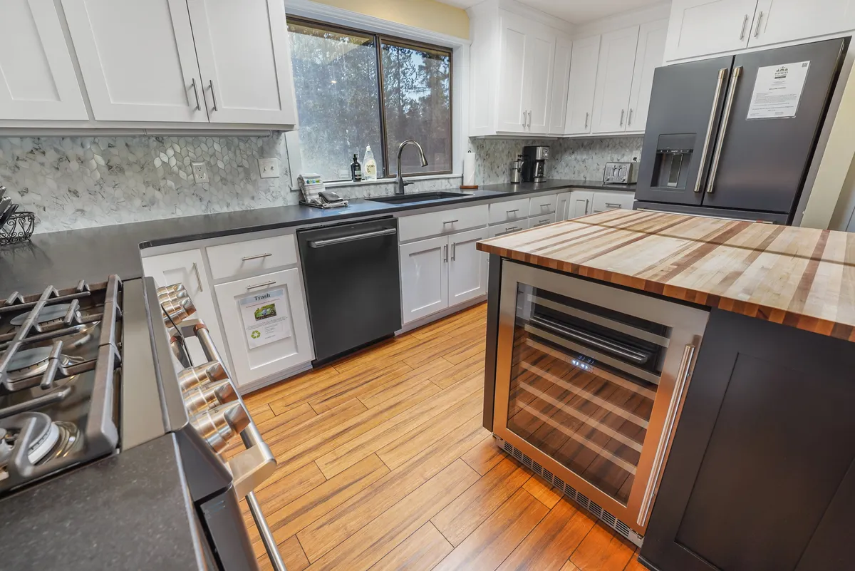 A kitchen scene highlighted by gleaming stainless steel appliances, a central island, and abundant natural light from a nearby window. The area appears ready for meal preparation and group cooking, inviting participation from all ages.