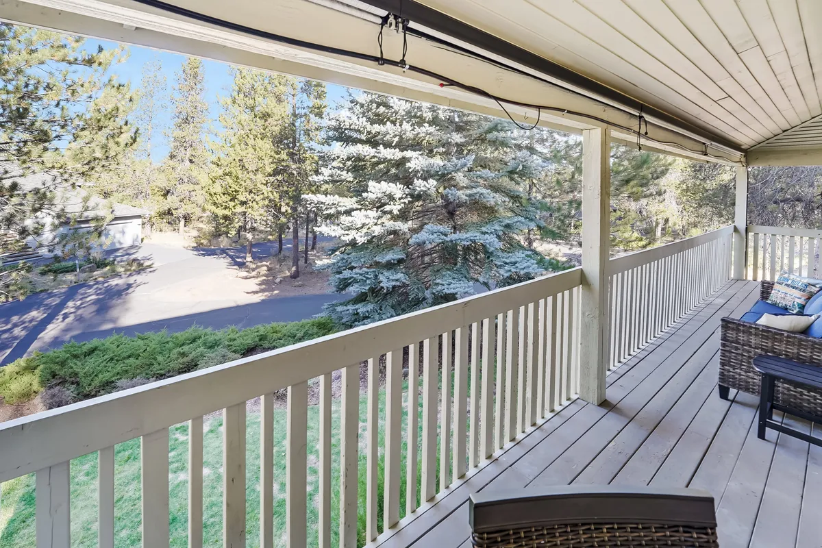 The photo shows a serene balcony seating area surrounded by trees, offering a peaceful retreat with views of the surrounding natural landscape. The outdoor setting is ideal for unwinding, enjoying a morning coffee, or spotting wildlife.